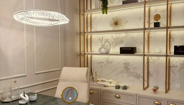 O consultório com a mesa de mármore verde, a luminária em anel e as estantes douradas